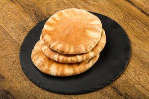 pan de pita sobre tablero de madera y fondo de madera foto