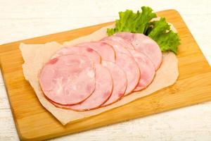 Sliced sausage on wooden board and wooden background photo