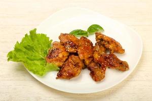 Teriyaki thighs on the plate and wooden background photo