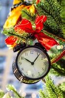 reloj de navidad lazo rojo en la rama de un árbol foto