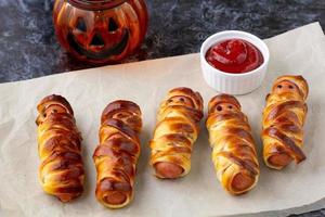 Scary sausage mummies in dough for kids party. Funny crazy Halloween food for children. photo