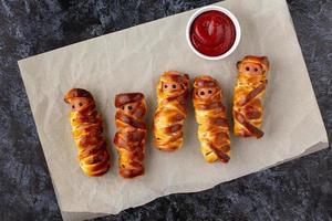 Scary sausage mummies in dough for kids party. Funny crazy Halloween food for children. photo