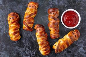 Scary sausage mummies in dough for kids party. Funny crazy Halloween food for children. photo