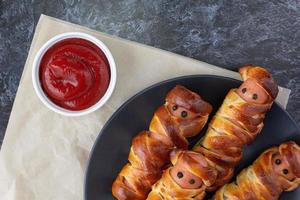 Scary sausage mummies in dough for kids party. Funny crazy Halloween food for children. photo