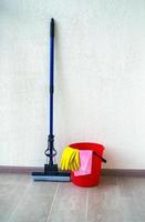 House cleaning. The photo shows a red bucket, rubber gloves, a rag and a mop.