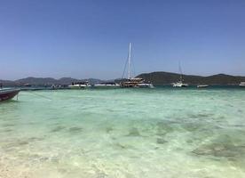 Thailand. Pictured is a beach with blue water. In the background is the yacht and the shore. photo