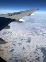 View from the airplane window. In the photo, the view from the window, the wing of the plane, mountains, snow. photo