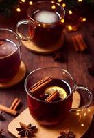 3d illustration of steaming hot mulled wine in glass mug on wooden background, cinnamon sticks, christmas mood photo