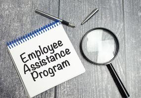 word EAP Employee Assistance Program text on white paper and magnifier photo