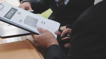 Business and lawyers discussing contract papers with brass scale on desk in office. Law, legal services, advice, justice and law concept picture with film grain effect video