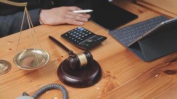 Business and lawyers discussing contract papers with brass scale on desk in office. Law, legal services, advice, justice and law concept picture with film grain effect video