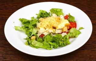 Caesar salad on the plate and wooden background photo