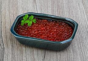 Red caviar in a bowl on wooden background photo