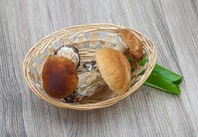 hongos silvestres en una canasta sobre fondo de madera foto