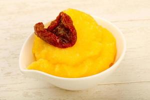 Polenta in a bowl on wooden background photo