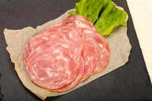 Sliced sausage on wooden board and wooden background photo