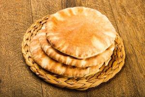 pan de pita sobre tablero de madera y fondo de madera foto