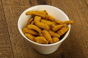 Tumeric roots in a bowl on wooden background photo