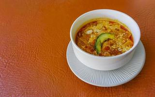 Vegetable soup with carrots greens onions tomato in white bowl. photo