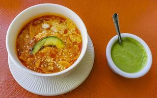 Vegetable soup with carrots greens onions tomato in white bowl. photo