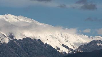 moln virvla runt över de snöig bergsrygg. Timelapse av de rörelse av moln i de berg. pittoresk peyzhas av de bergig kaukasus video
