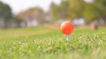 A closeup shot of an orange golf ball in a course photo