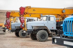 una fila de grandes camiones grúa y máquinas en un sitio de construcción industrial foto