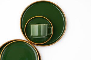 A set of dark green ceramic tableware with orange outlines on a white background photo