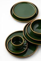 A set of dark green ceramic tableware with orange outlines on a white background photo