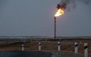 A beautiful shot of the evening highway and burning roof of the construction of the factory in the background photo