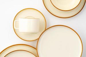 A set of white and brown ceramic plate and cup on a white background. Top view photo