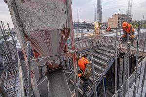 los trabajadores en un techo de infraestructura de construcción con maquinaria y herramientas. verter hormigón en un molde foto