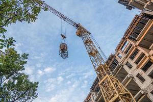 A low angle shot of a crane with equipment on a construction site with a new building infrastructure. Pouring concrete into a mold photo