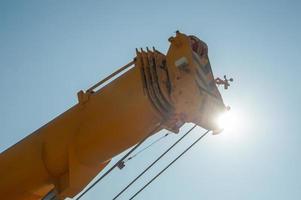 A closeup of a track crane tower against a sunny sky photo