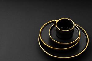 un juego de platos y tazas de cerámica negra y dorada sobre un fondo negro