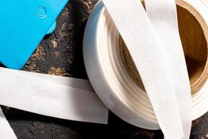 A closeup shot of a roll of white ribbon and a blue paper tag for fabric photo