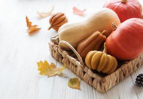 Autumn decorative pumpkins with fall leaves on wooden background. photo