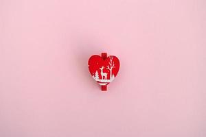 Red wooden Christmas and New Year decoration in the form of heart on a pink background, top view. photo