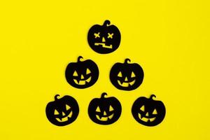 Holiday decorations for Halloween. Black paper pumpkins on a yellow background, top view. photo