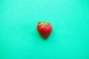 Ripe red strawberry on a turquoise background, top view. Healthy summer food. photo