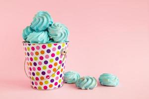 Small colorful bucket filled with blue meringue on a pink pastel background. Minimal concept with copy space. photo