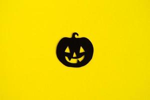 Holiday decorations for Halloween. Black paper pumpkin in the center on a yellow background, top view. photo