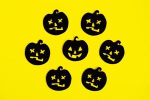 Holiday decorations for Halloween. Black paper pumpkins on a yellow background, top view. photo