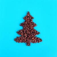 Christmas tree made from coffee beans on a blue background, top view. photo