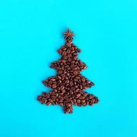 árbol de navidad hecho de granos de café y estrella de anís decorada sobre un fondo azul, vista superior. foto