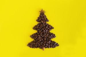 composición invernal con árbol de navidad hecho con granos de café y estrella de anís decorada y canela sobre un fondo amarillo, puesta plana. tarjeta de felicitación para año nuevo con espacio de copia. foto