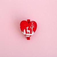 Red wooden Christmas and New Year decoration in the form of heart on a pink background, top view. photo