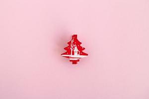 Red wooden Christmas and New Year decoration in the form of Christmas tree on a pink background, top view. photo