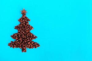 Christmas tree made from coffee beans and decorated anise star on a blue background, top view. photo