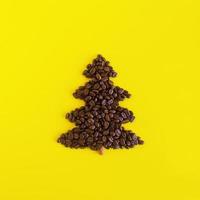 Winter composition with Christmas tree made by coffee beans and decorated cinnamon stick on a yellow background, flat lay. Greeting card for New Year with copy space. photo